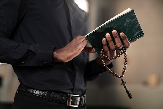 Junger männlicher Priester mit einer Bibel und einem Rosenkranz