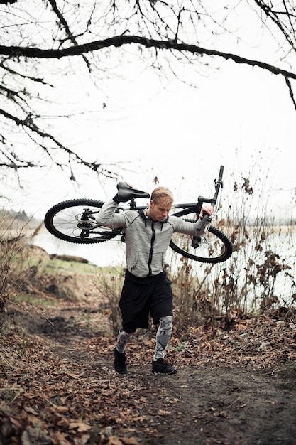 Kostenloses Foto junger männlicher radfahrer, der seine mountainbike trägt