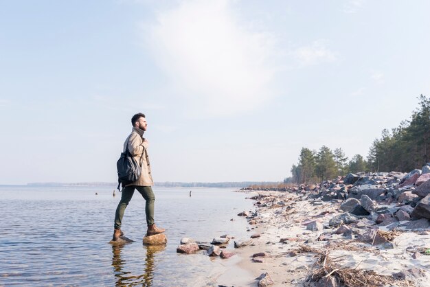 Junger männlicher Reisender mit ist der Rucksack, der Ansicht betrachtet