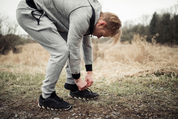 Junger männlicher Rüttler, der seine Sportschuhe setzt