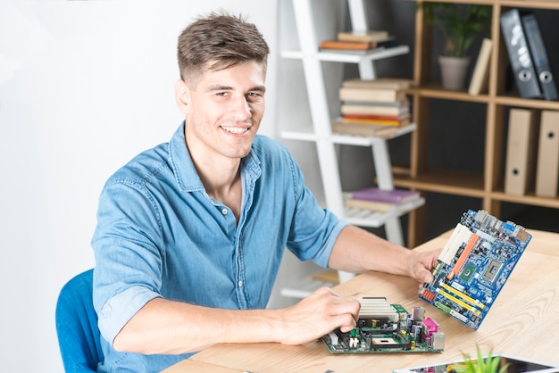 Junger männlicher Techniker, der Motherboard hält