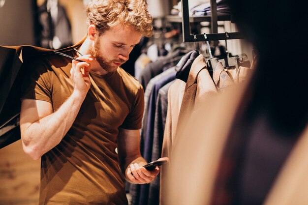 Junger Mann am Herrenbekleidungsshop sprechend am Telefon