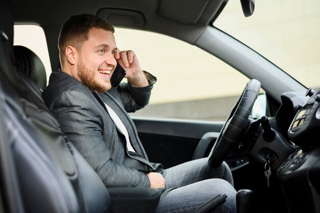 Junger Mann am Steuer mit seinem Telefon am Ohr