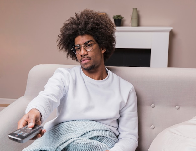 Junger Mann auf der Couch mit Fernbedienung