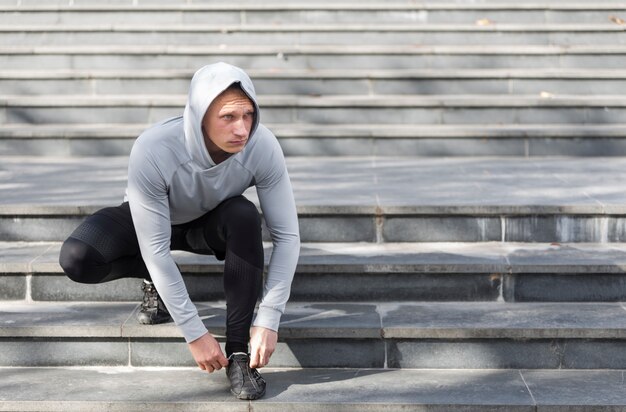 Junger Mann auf der Treppe, die seine Spitzee bindet