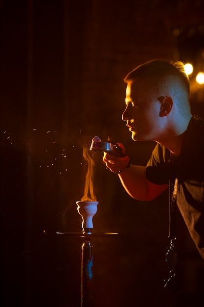 Junger Mann dampft von einer Wasserpfeife in einer Bar