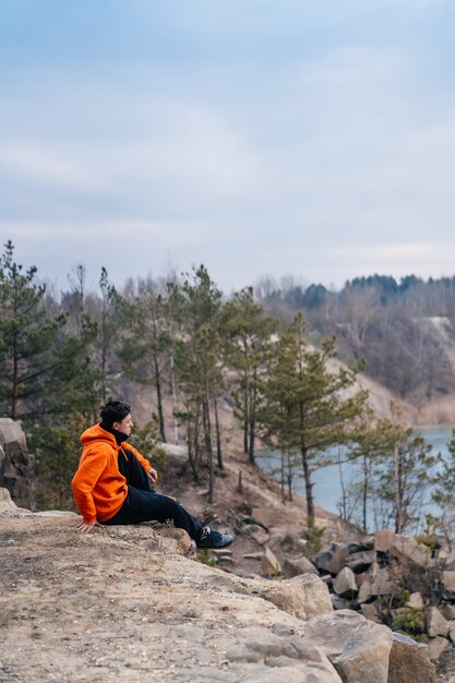 Junger Mann, der am Rand einer Klippe sitzt