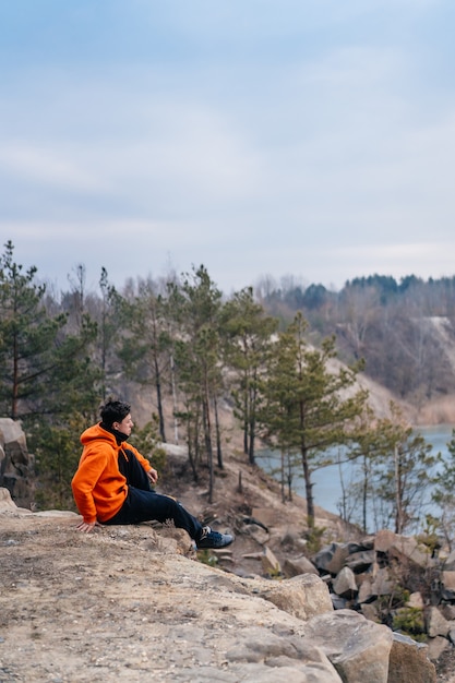 Junger Mann, der am Rand einer Klippe sitzt