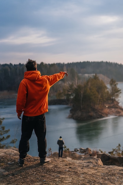 Kostenloses Foto junger mann, der am rand einer klippe und des zeigens steht