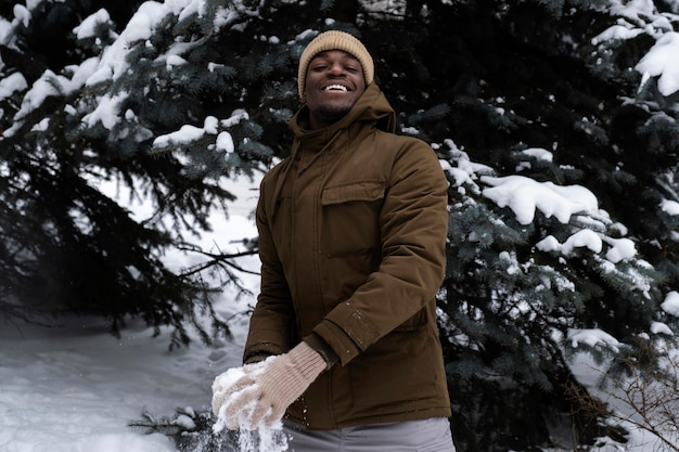 Kostenloses Foto junger mann, der am wintertag im freien mit schnee spielt