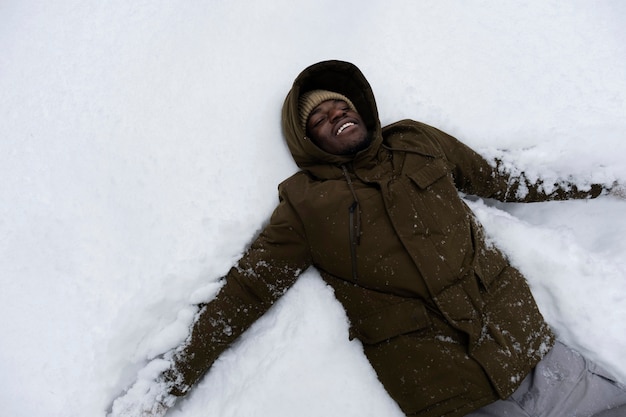 Kostenloses Foto junger mann, der am wintertag im freien mit schnee spielt
