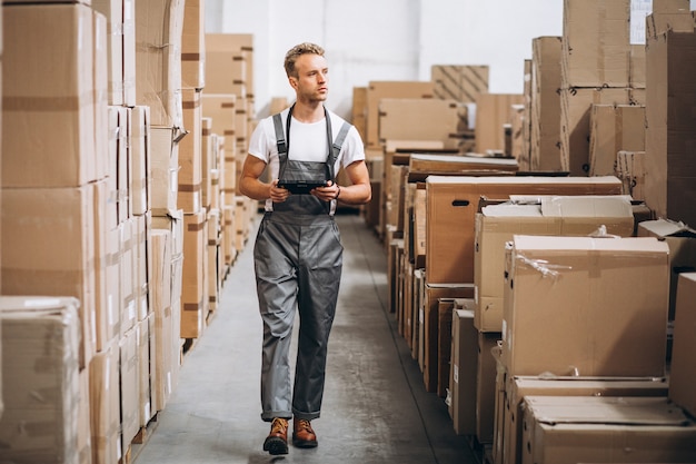 Junger Mann, der an einem Lager mit Kästen arbeitet