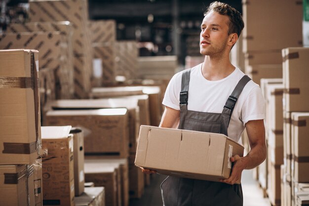 Junger Mann, der an einem Lager mit Kästen arbeitet