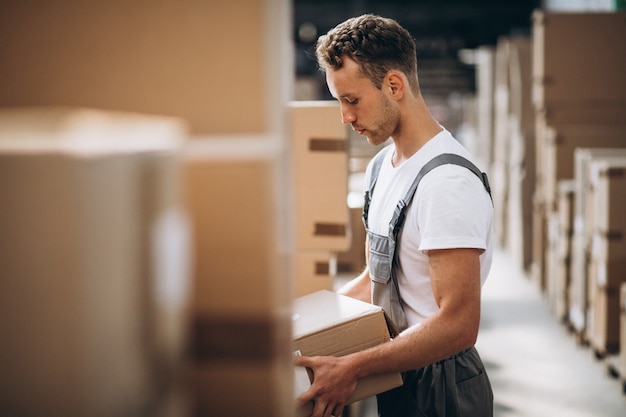 Junger Mann, der an einem Lager mit Kästen arbeitet