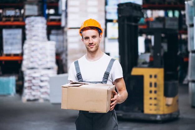 Junger Mann, der an einem Lager mit Kästen arbeitet