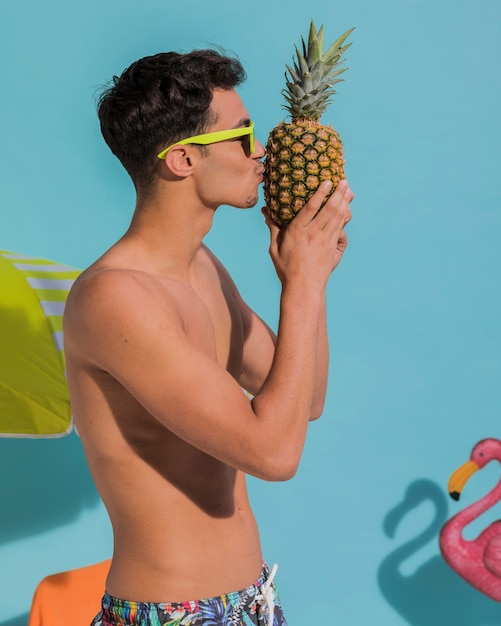 Junger Mann, der Ananas küsst