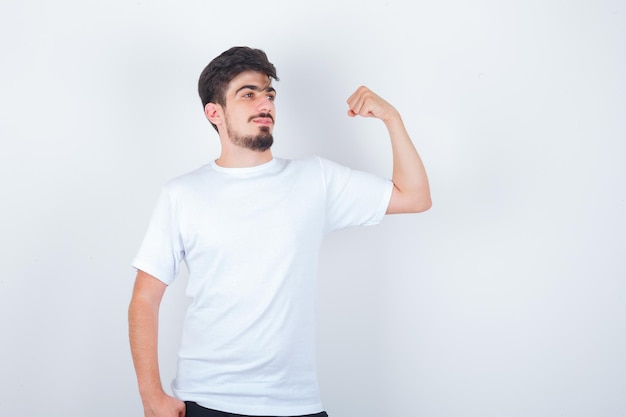 Junger Mann, der Armmuskeln im weißen T-Shirt zeigt und selbstbewusst aussieht