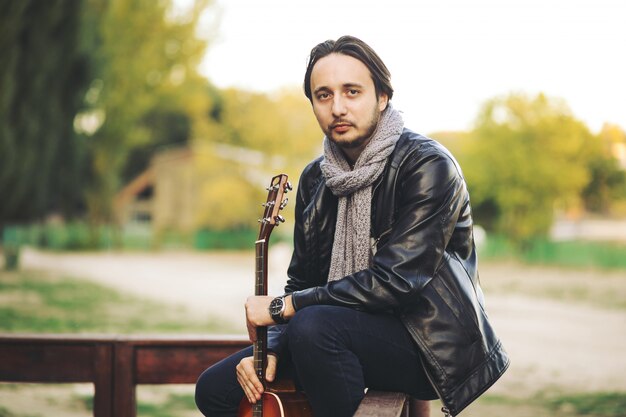 Junger Mann, der auf Gitarre am See spielt