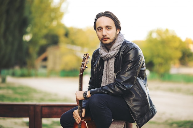 Junger Mann, der auf Gitarre am See spielt