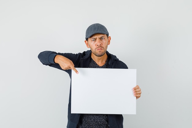 Kostenloses Foto junger mann, der auf leere leinwand im t-shirt zeigt