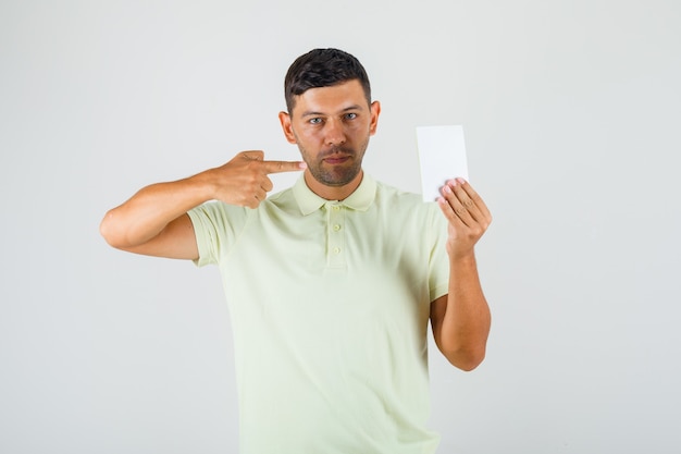 Junger Mann, der auf leeres Papier im T-Shirt zeigt