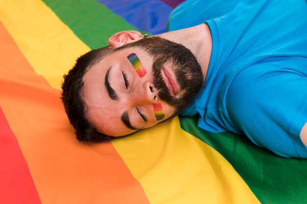 Junger Mann, der auf mehrfarbige LGBT-Flagge legt