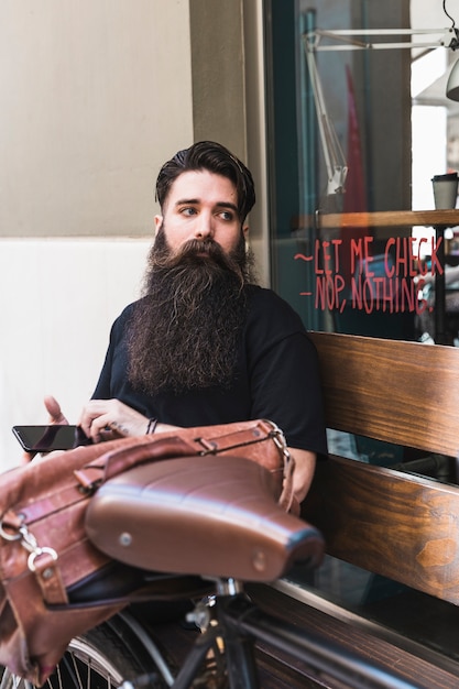 Junger Mann, der außerhalb des Cafés mit seinem Fahrrad sitzt