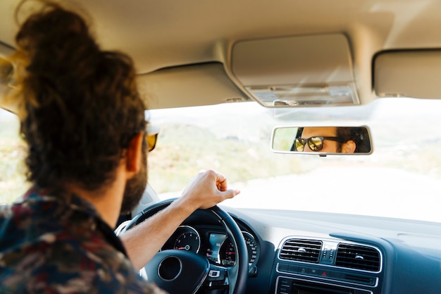 Junger Mann, der Auto am sonnigen Tag fährt