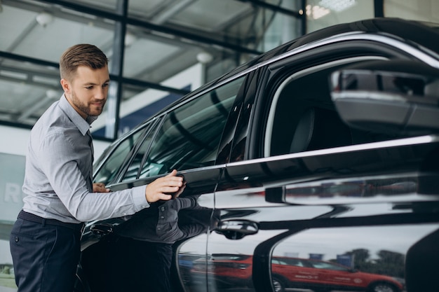 Junger Mann, der Autoschlüssel an seinem neuen Auto hält