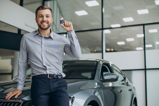 Junger Mann, der Autoschlüssel an seinem neuen Auto hält