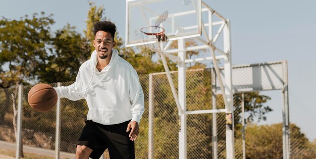 Junger Mann, der Basketball mit Kopienraum spielt