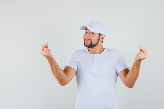 Junger Mann, der beim Meditieren im weißen T-Shirt, in der Mütze und in der entspannten Vorderansicht aufwirft.