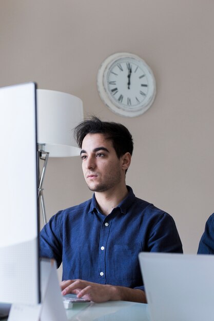 Junger Mann, der Computer im Büro verwendet