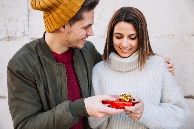 Junger Mann, der der Frau Geschenk gibt