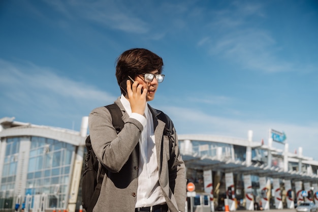 Junger Mann, der draußen auf Smartphone spricht. Kommunikationskonzept. Vorderansicht.