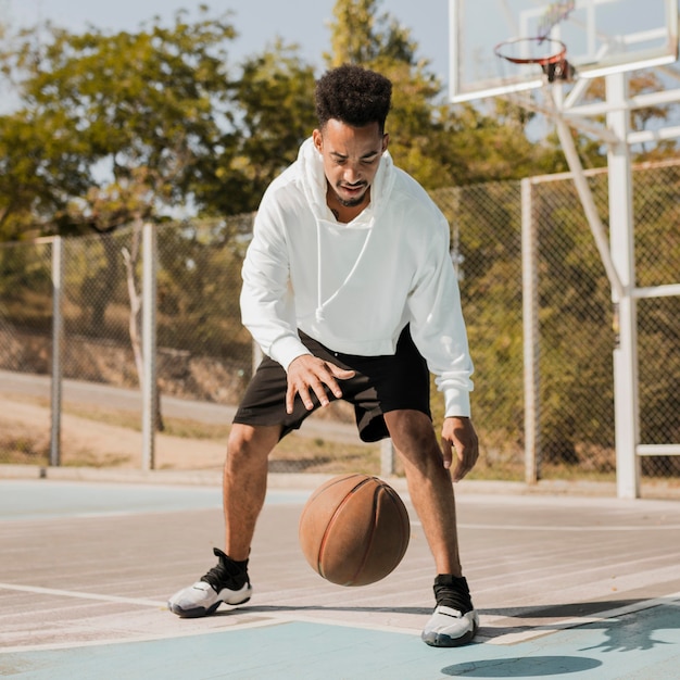 Junger Mann, der draußen Basketball spielt