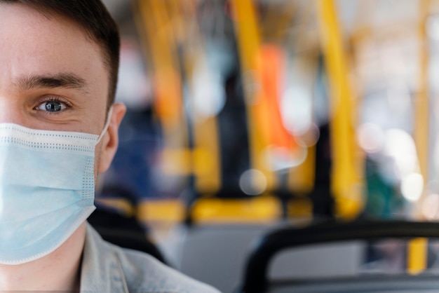 Junger Mann, der durch Stadtbus reist, der chirurgische Maske trägt