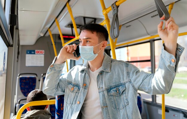 Junger Mann, der durch Stadtbus unter Verwendung des Smartphones reist