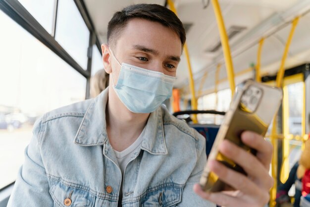 Junger Mann, der durch Stadtbus unter Verwendung des Smartphones reist