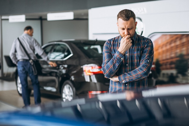 Junger Mann, der ein Auto in einem Autosalon wählt