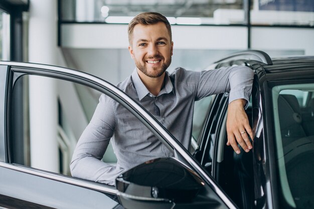 Junger Mann, der ein Auto in einem Autosalon wählt