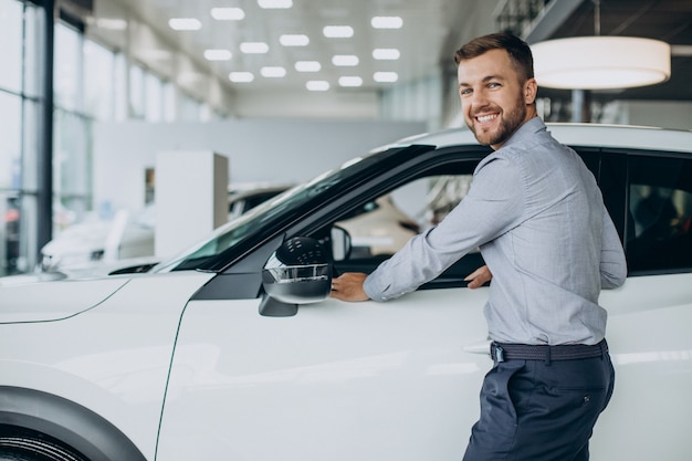 Junger Mann, der ein Auto in einem Autosalon wählt