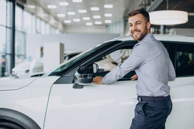 Junger Mann, der ein Auto in einem Autosalon wählt