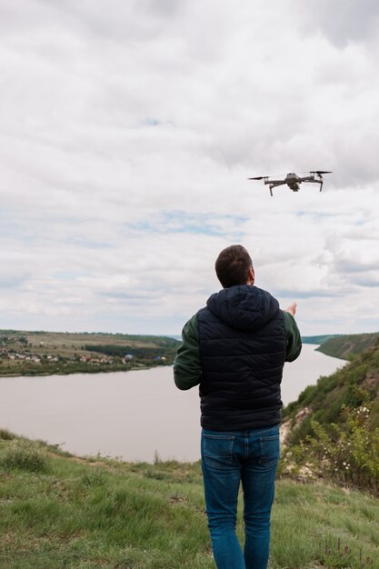 Junger Mann, der eine Drohne in der Natur steuert