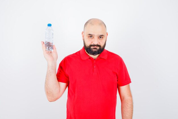 Junger Mann, der eine Flasche in der Vorderansicht des roten Hemdes hält.