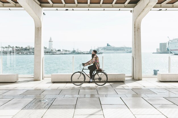 Junger Mann, der Fahrrad nahe dem Hafen fährt