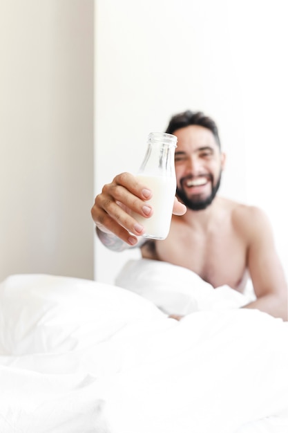 Junger Mann, der Flasche Milch zeigt