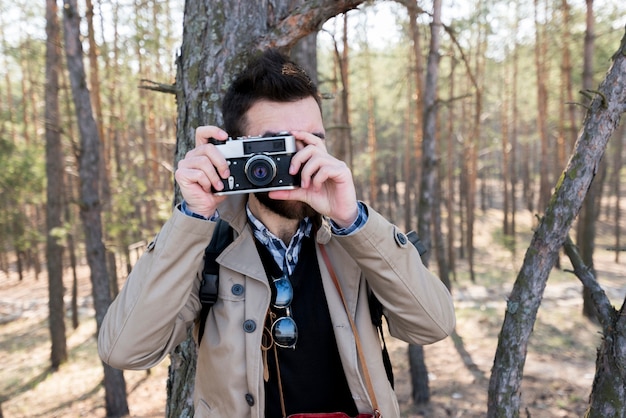 Junger Mann, der Foto mit Kamera im Wald macht