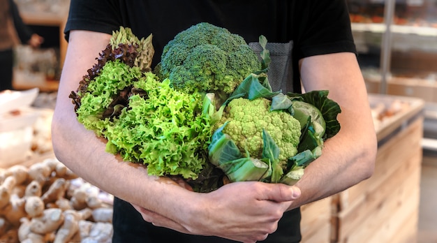 Kostenloses Foto junger mann, der gemüse am markt kauft