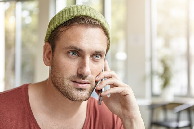 Junger Mann, der im Café sitzt und am Telefon spricht